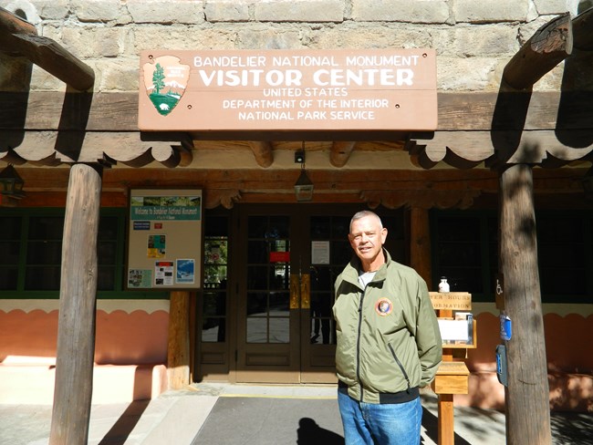 A man stands in front of the Bandelier National Monument visitor center
