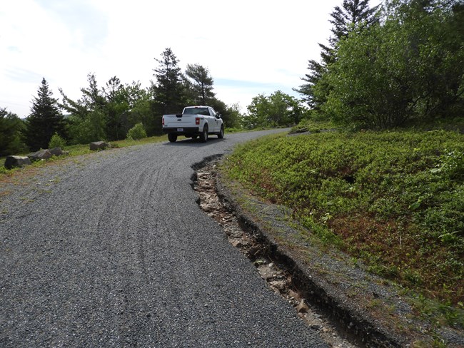 a park vehicle on a carriage road curve behind a deep washout