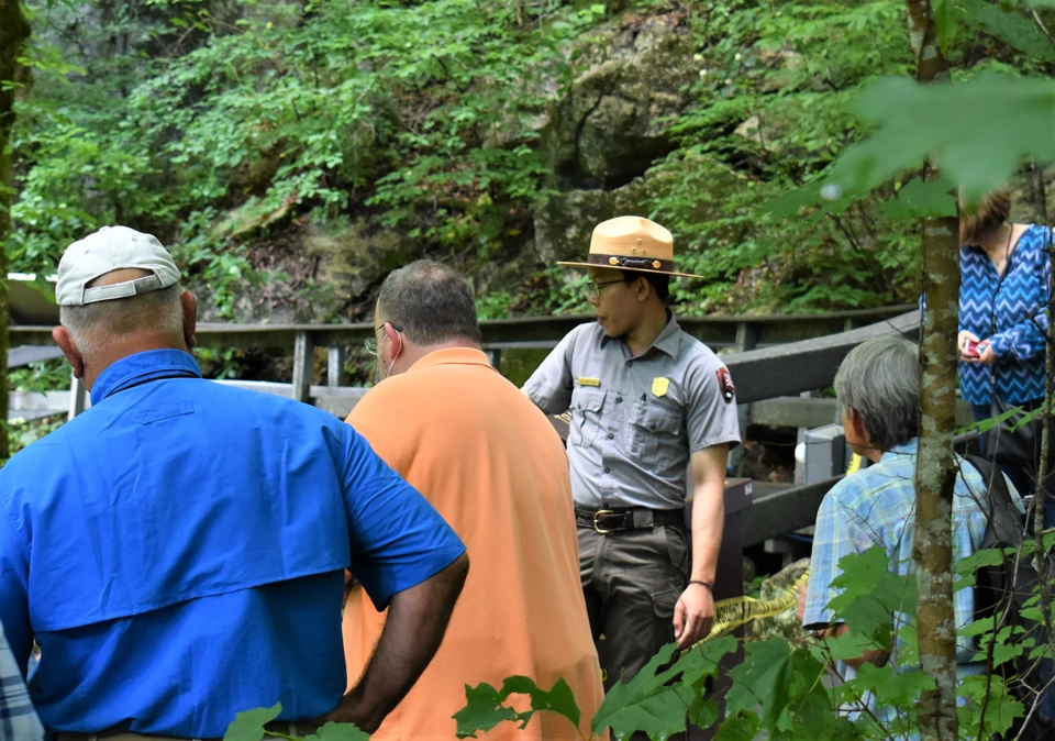 Rangers give great advice A male ranger points over a gray boardwalk as a group of visitors watch on.