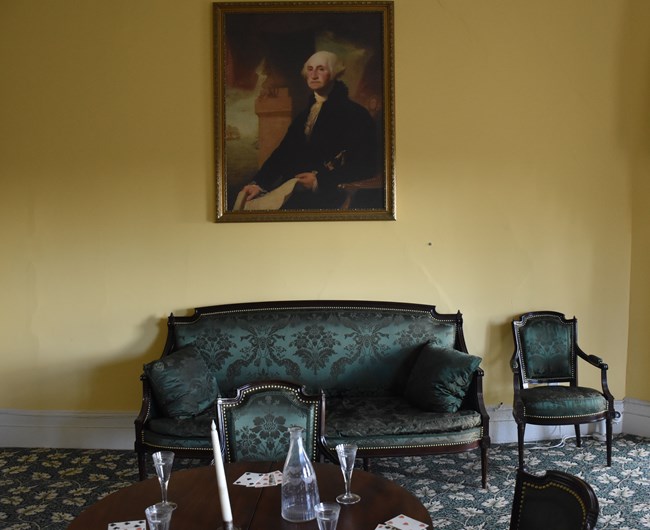 Portrait of George Washington hangs about a green sofa in Hamilton's parlor.