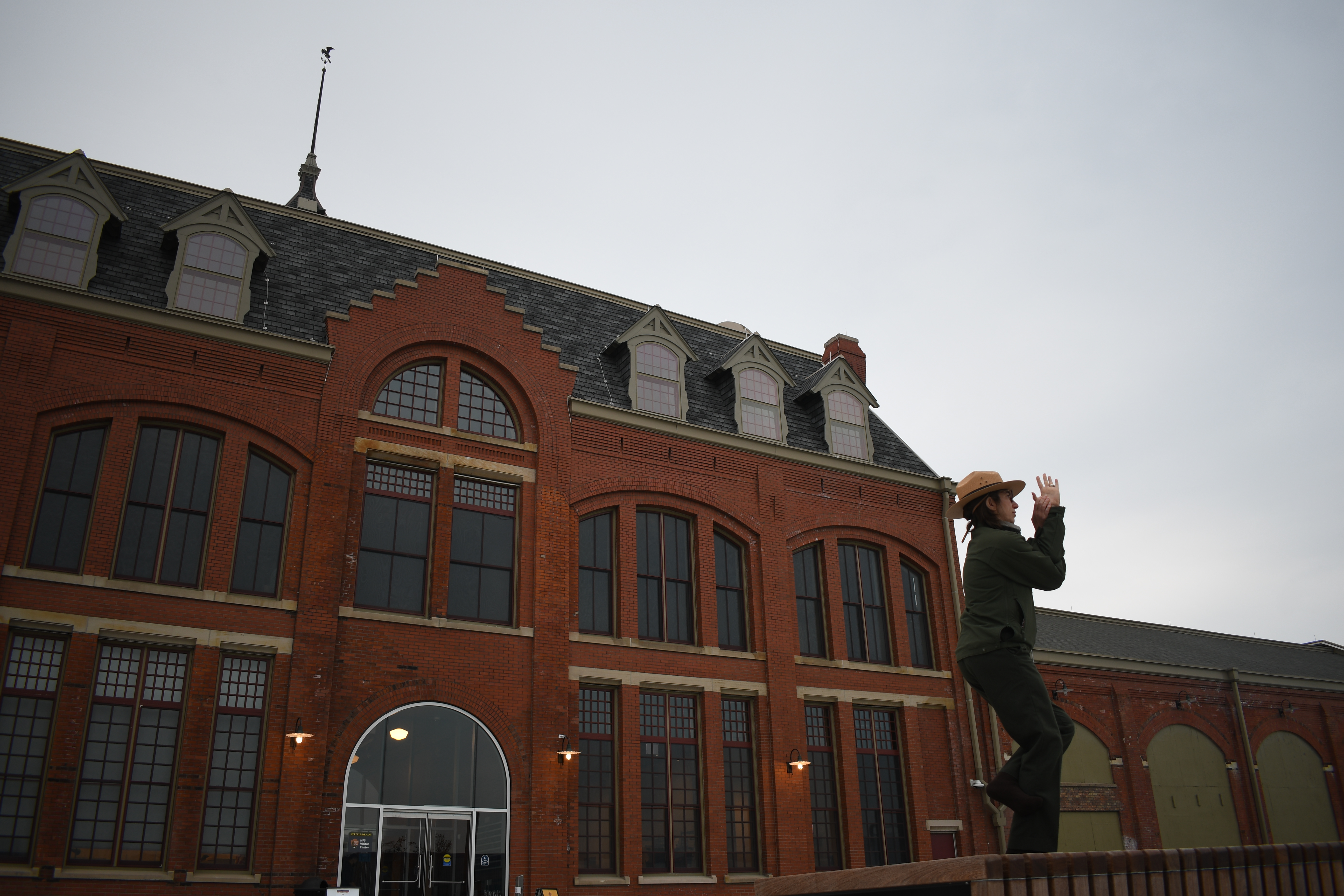 A Ranger stands atop a bench doing an eagle yoga pose. A clock stands tall behind her.