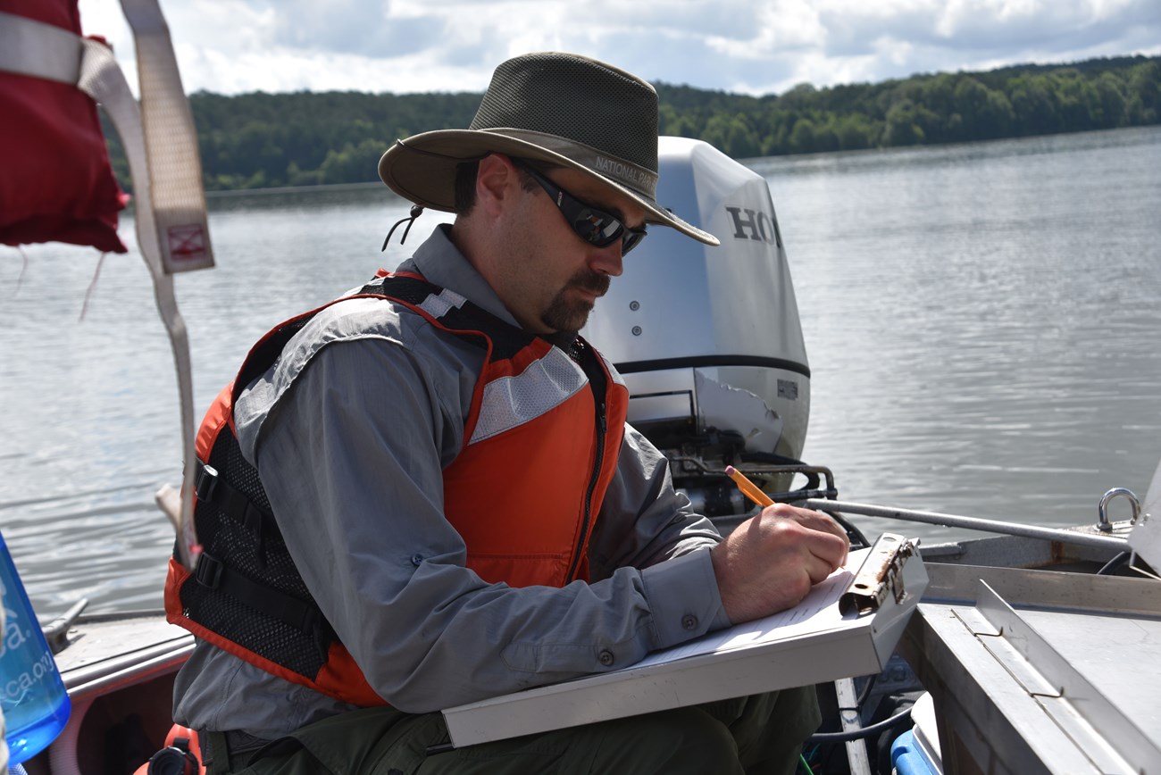 Eric Starkey, SECN Aquatic Ecologist Man in uniform writing on a clipboard