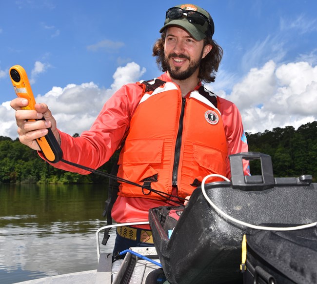 man wearing a life vest holding a weather gauge