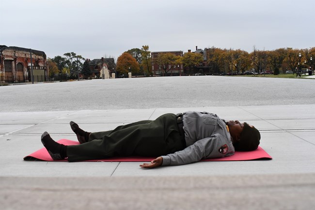 A ranger lays in the imprint of a sleeping car on the ground, enjoying some rest.