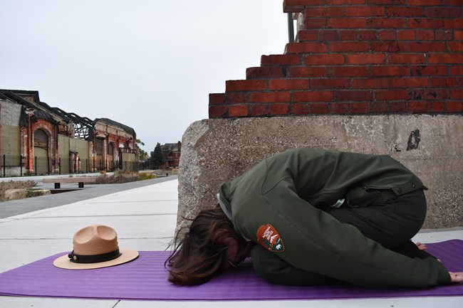 A ranger practices brick pose next to cascading remains of brick from once standing building.