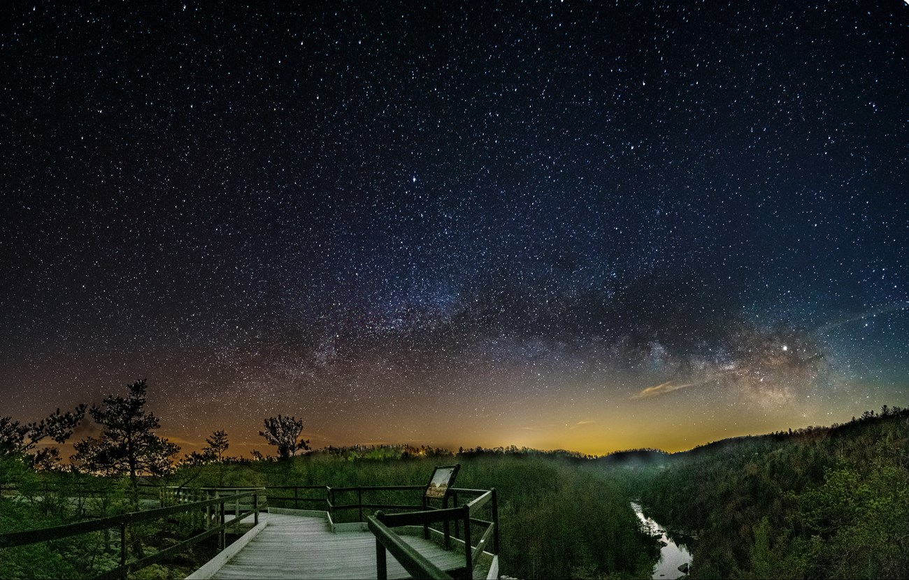 The milky way and stars above a boardwalk and stream
