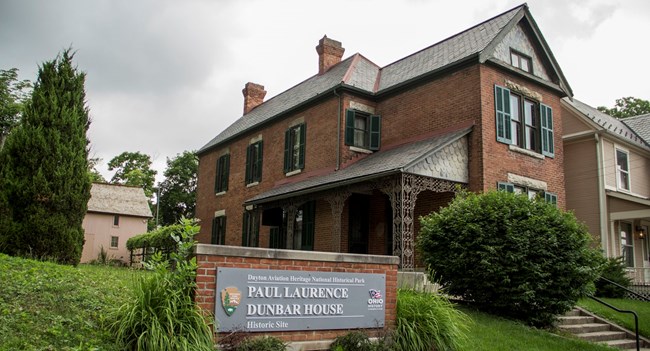 Two-story brick historic home with a sign reading Paul Laurence Dunbar House Historic Site