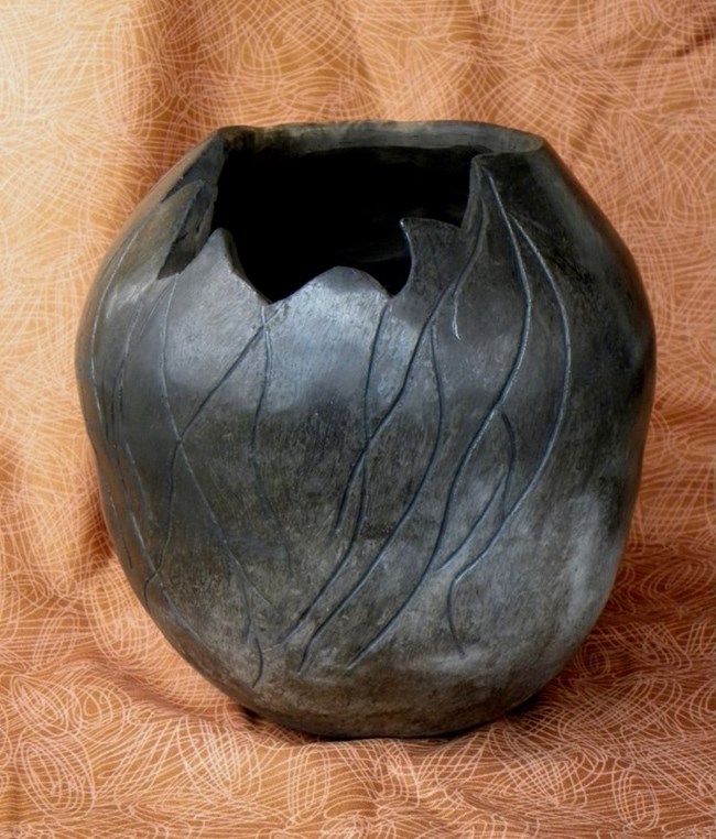 A pot with a shiny black finish and artistic markings.