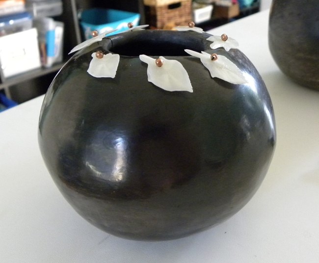 A shiny black pot with white fish scales along the opening.