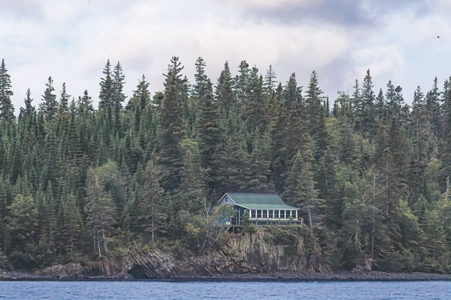 A photo taken from the water of a cabin on Tobin Harbor surrounded by trees