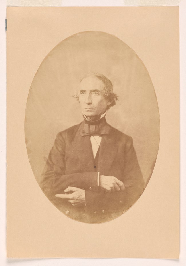 Sepia colored salt print photo of a man wearing a suit and bow tie.