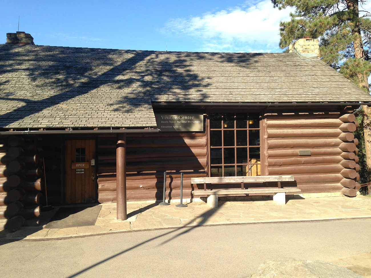 Devil's Tower National Monument's historic visitor center Brown log building with sign on the front that says "Visitor Center Devil's Tower National Monument."