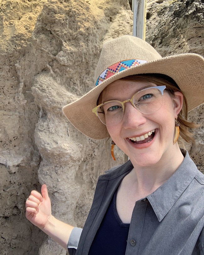 a person standing next a fossil that is exposed rock outcrop