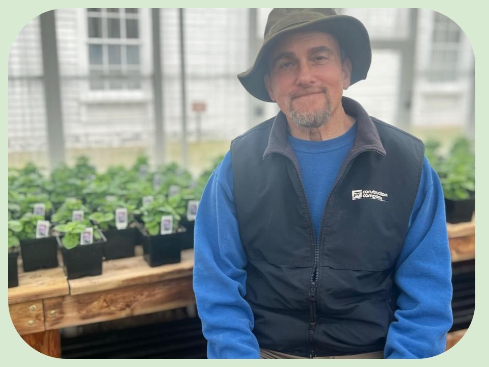 Di Salvo, Mike Chatham garden volunteer Mike Di Salvo seated inside one of the Chatham green houses with plant saplings in the background.