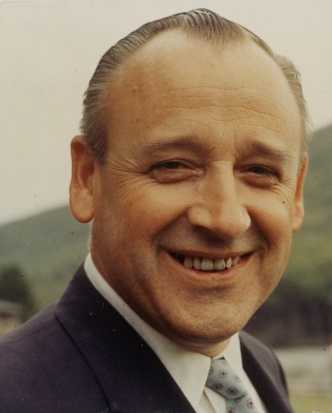 Color photo of a smiling George B. Hartzog, Jr. with hills in the background.