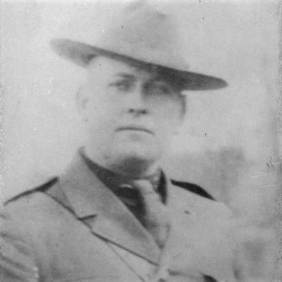 Black and white photo of a male police offer, with wide brimmed hat and a tie