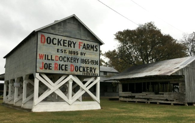 Historic farm buildings, one with name of farm and owners names painted on the side.