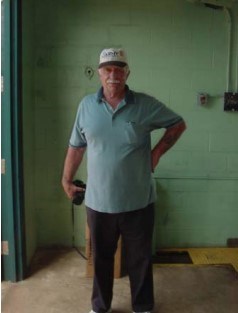 an older man stands in front of a green wall