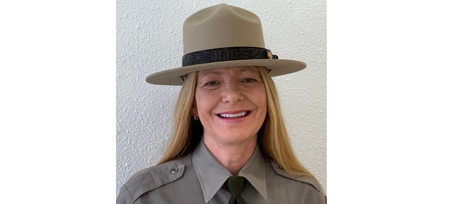 Smiling woman with long blonde hair in NPS dress uniform and hat