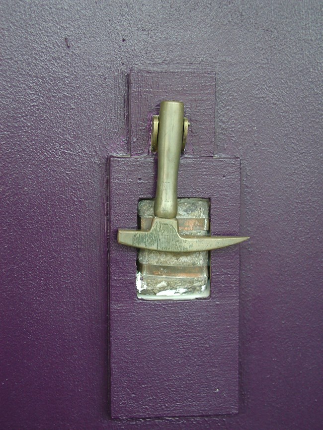 Door knocker detail A door knocker in the shape of a rock hammer hangs on a purple door