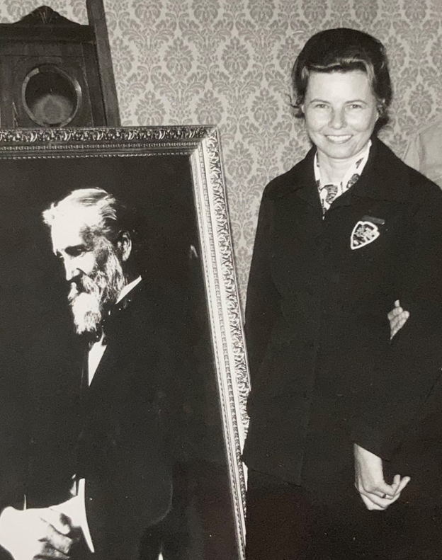 Doris Omundson in uniform, smiling next to a photo of John Muir