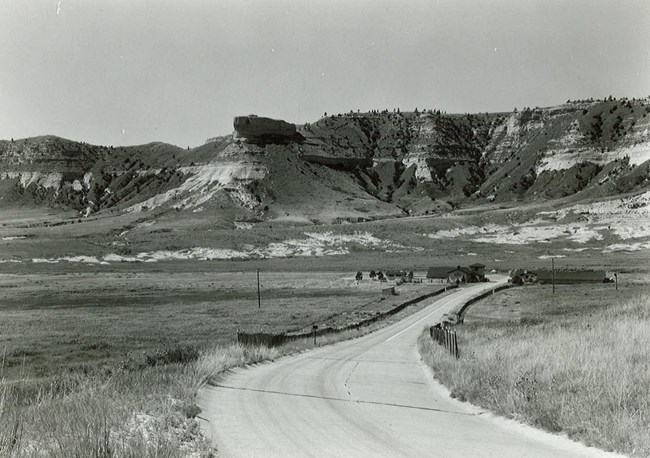 A road winds up towards a sandstone bluff.