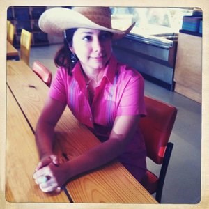 Photo of the presenter wearing a straw hat, seated at a rustic table.