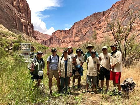 Group of National Park Service staff and Southwest Conservation Corps members posing in front of a desert canyon.