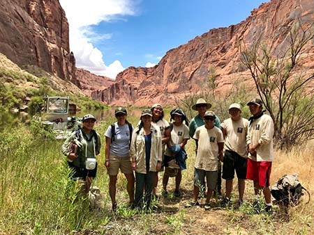 Southwest Conservation Corps Group of National Park Service staff and Southwest Conservation Corps members posing in front of a desert canyon.