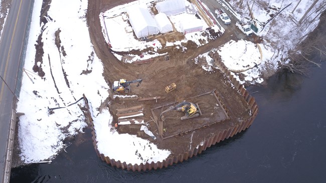 an aerial view from a drone of excavation work in the winter on an archeological site along a river