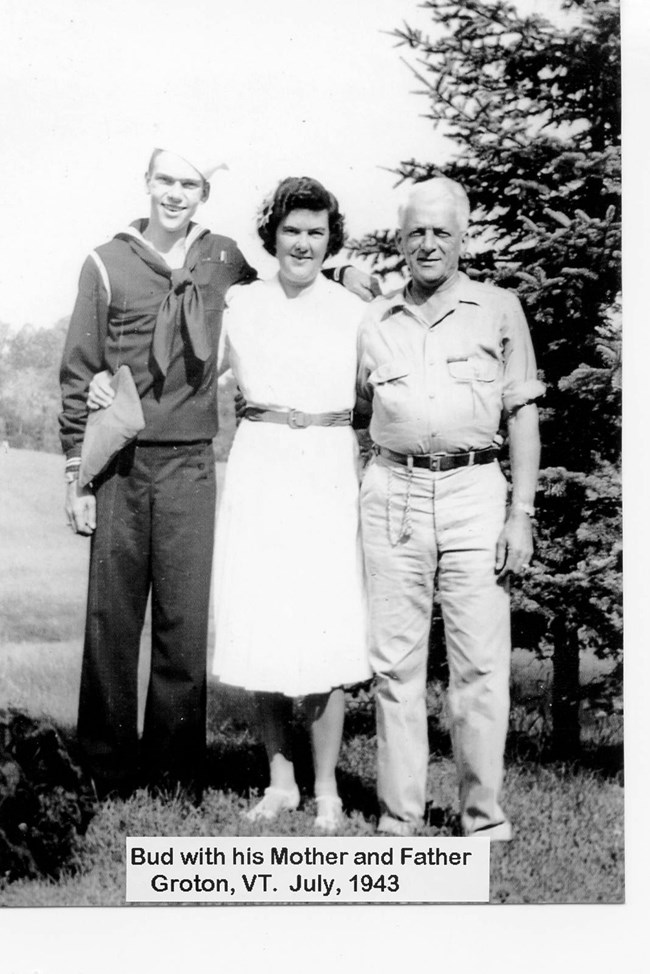 Man in sailor uniform stands with older man and woman.