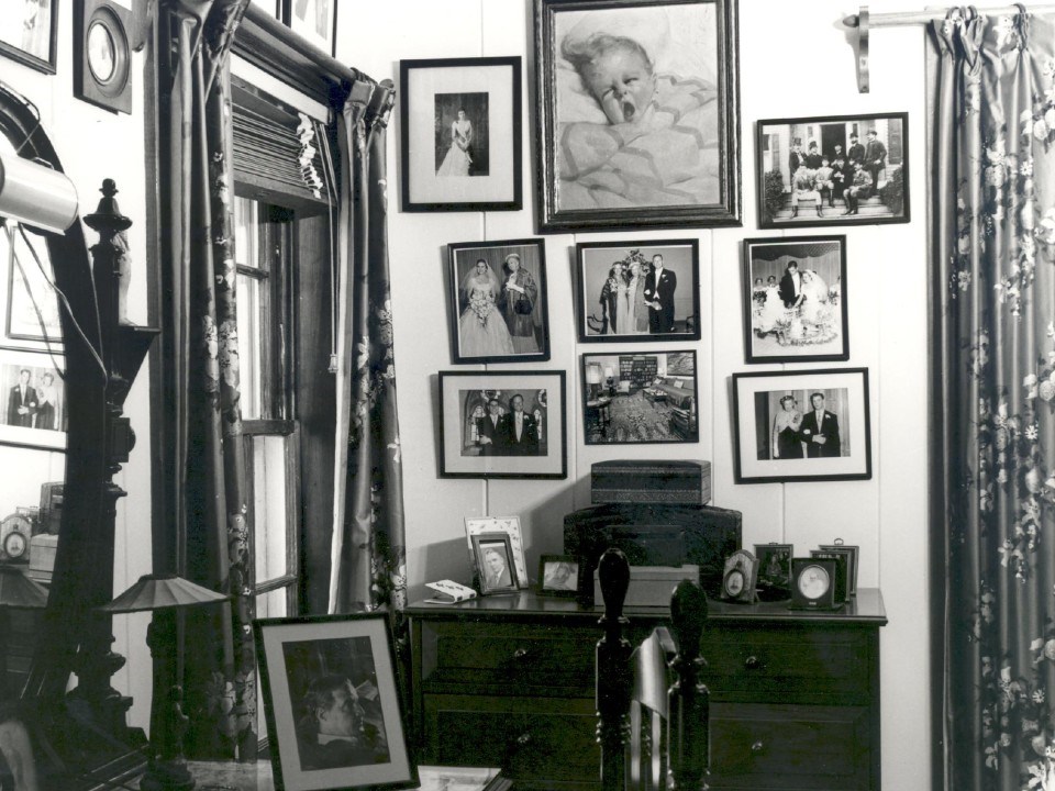A corner of a furnished room with many framed photographs hanging on the walls.