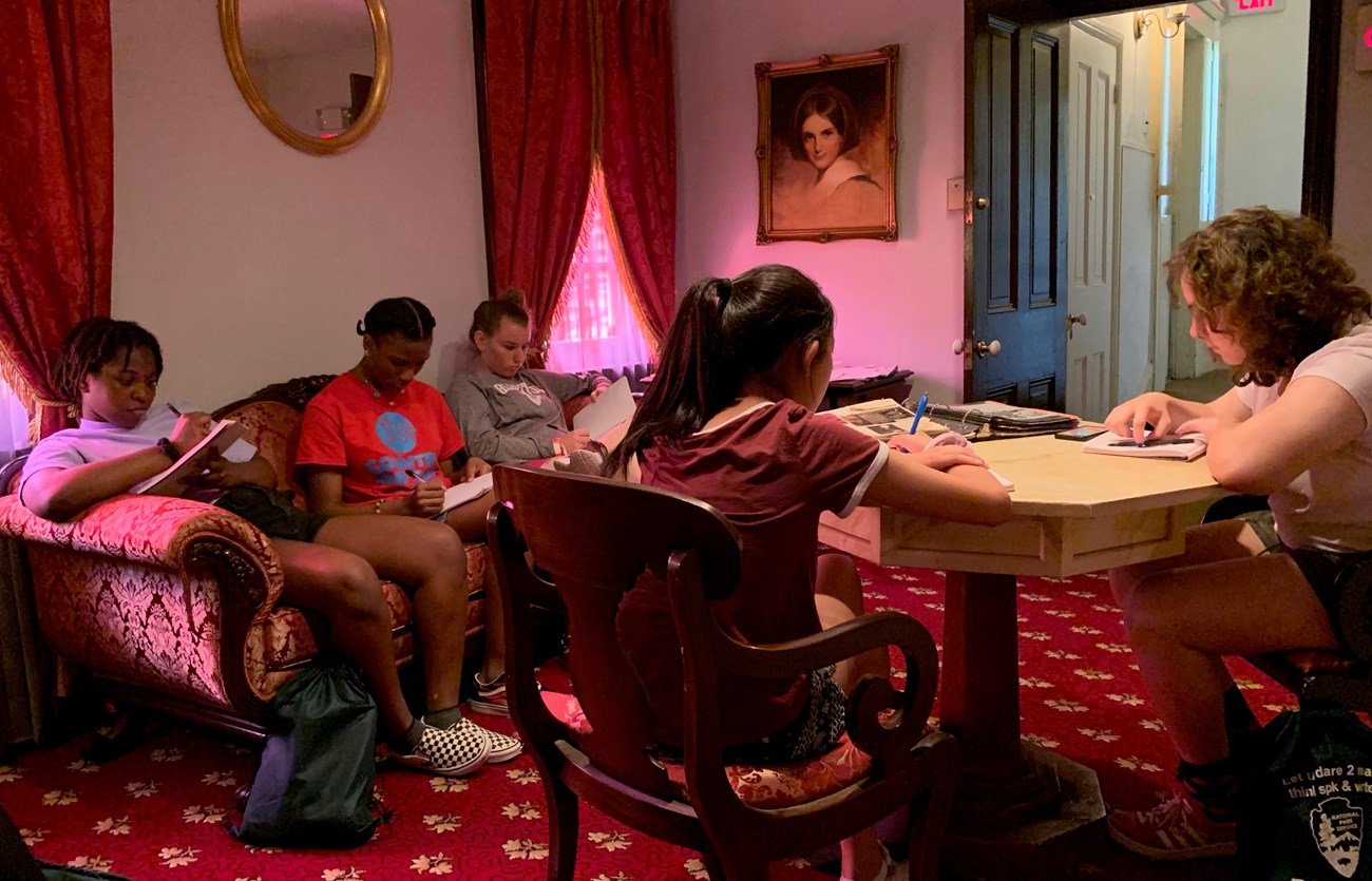 Students in a historic red-furnished parlor room