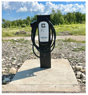 Electric vehicle charger in parking lot with blue sky background.