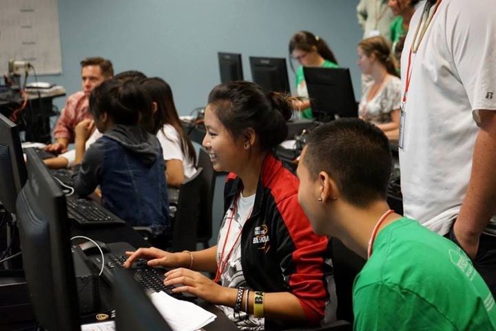 Asian female and male looking a two computer monitors.