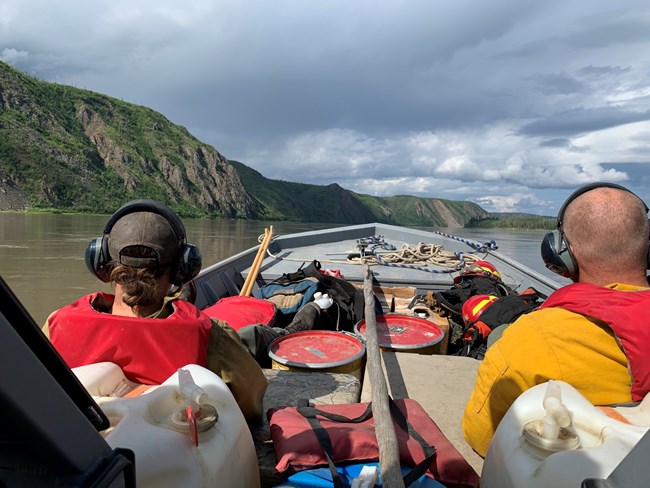 Alaska Eastern Area NPS firefighters travel by boat. Two people riding in a boat stacked with fire gear and equipment.
