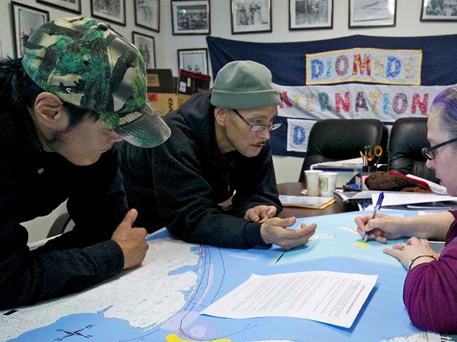 Two men look over maps.