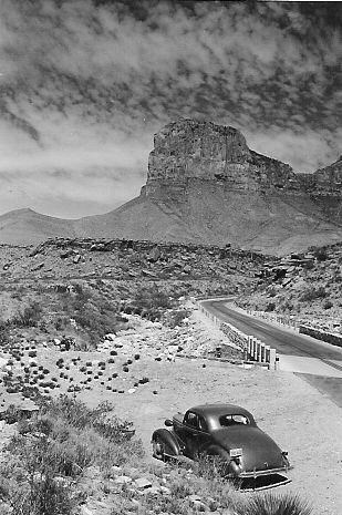 A historic photo of a 1940s car parked in front of the Guadalupe Mountains