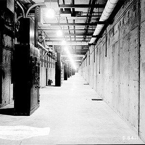 Electrical Gallery A black and white photo of a large, narrow, lit concrete hallway.