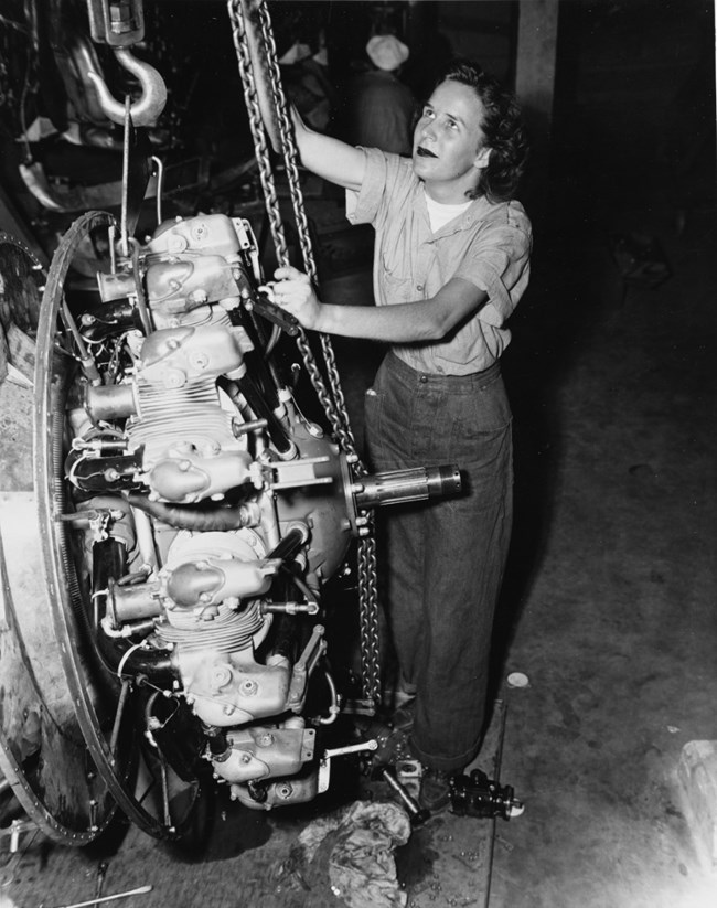 Elizabeth Abercrombie Naval Plane Black and white photo of a woman in button down and pants pulling a chain attached to an engine
