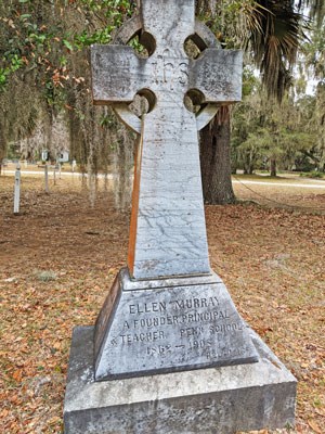 A single stone grave marker, carved in the shape of a cross