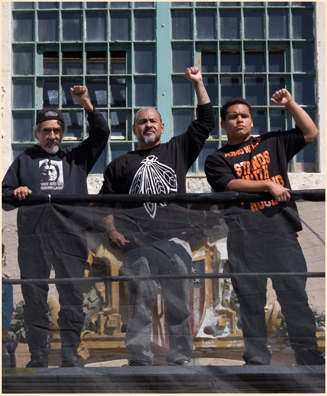 Eloy Martinez, Darren Laiwa, and Richard Oakes’ grandson, Elijah Oakes repaint “FREE” on the Alcatraz Cell House June 21, 2017