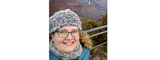 Woman in gray winter hat with blue scarf. wearing glasses