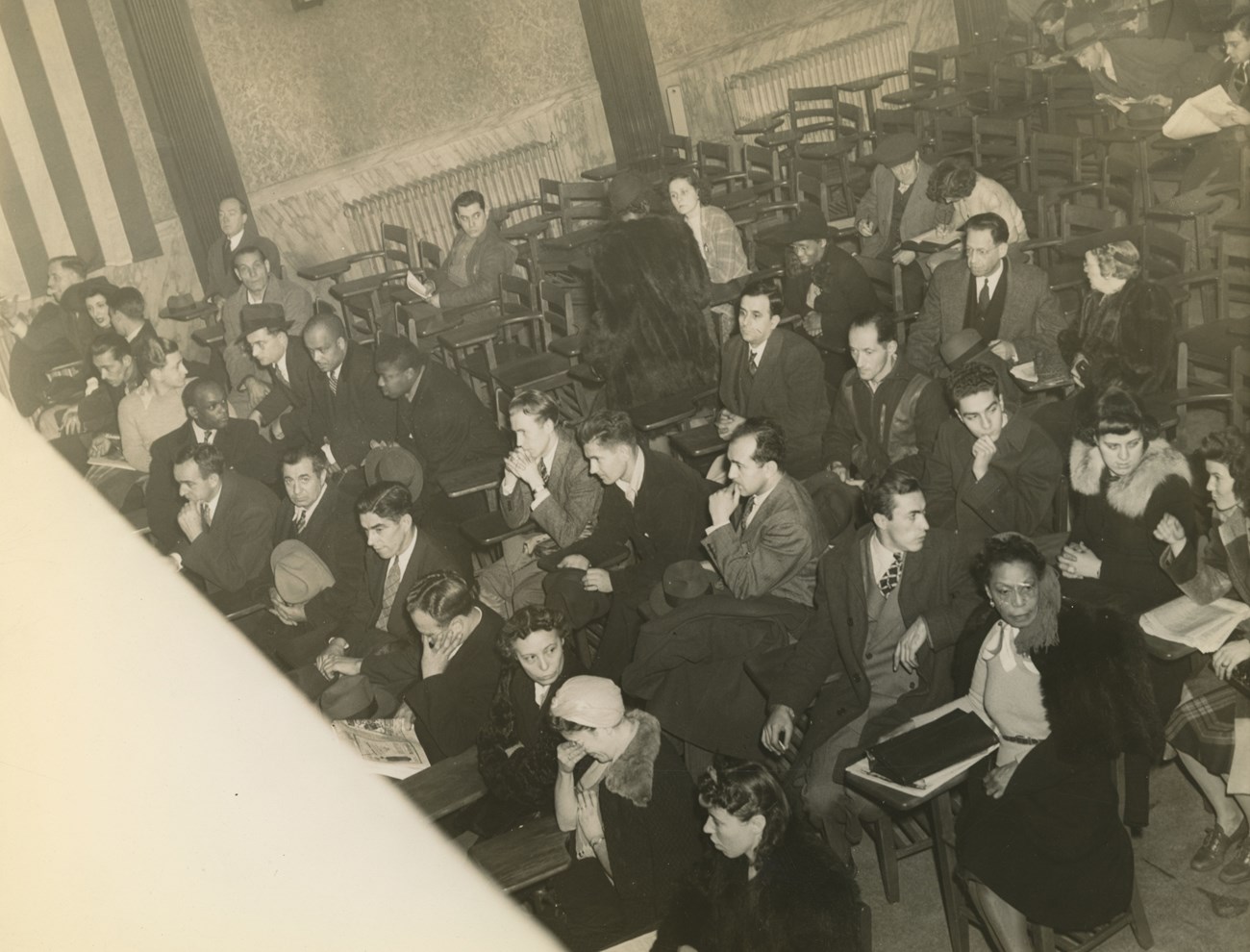 Wright Employment Office. Sepia photo of group of men and women of multiple races sitting in a room facing in one direction