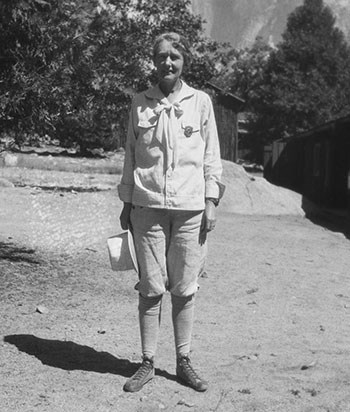 Ranger Enid Michael wearing her badge, breeches, knee socks and holding a brimmed hat.