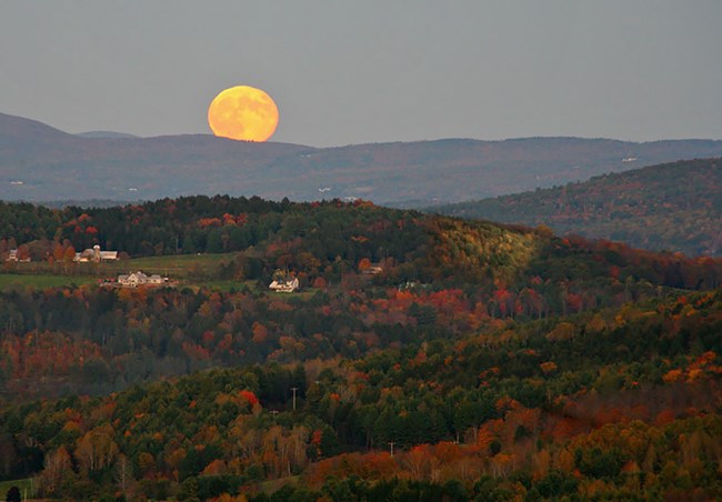 Panoramic view of Woodstock from the South Peak of Mount Tom a full moon rises over rolling hills painted in fall colors
