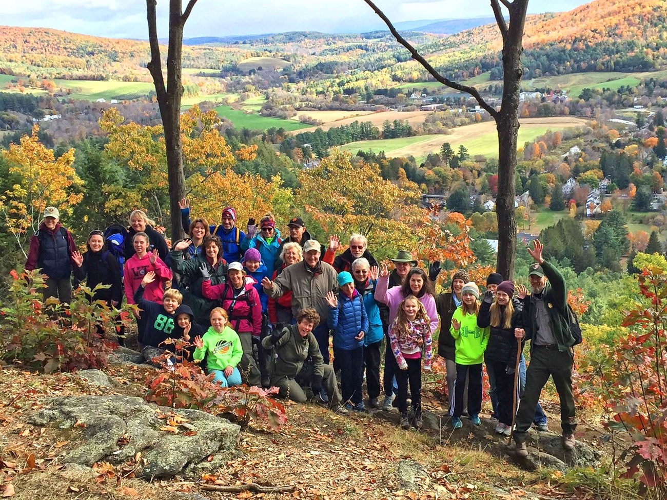 Ranger guided hike on Mt. Tom a group of people of varying ages gather with park ranger guides on a rolling hill view in the fall