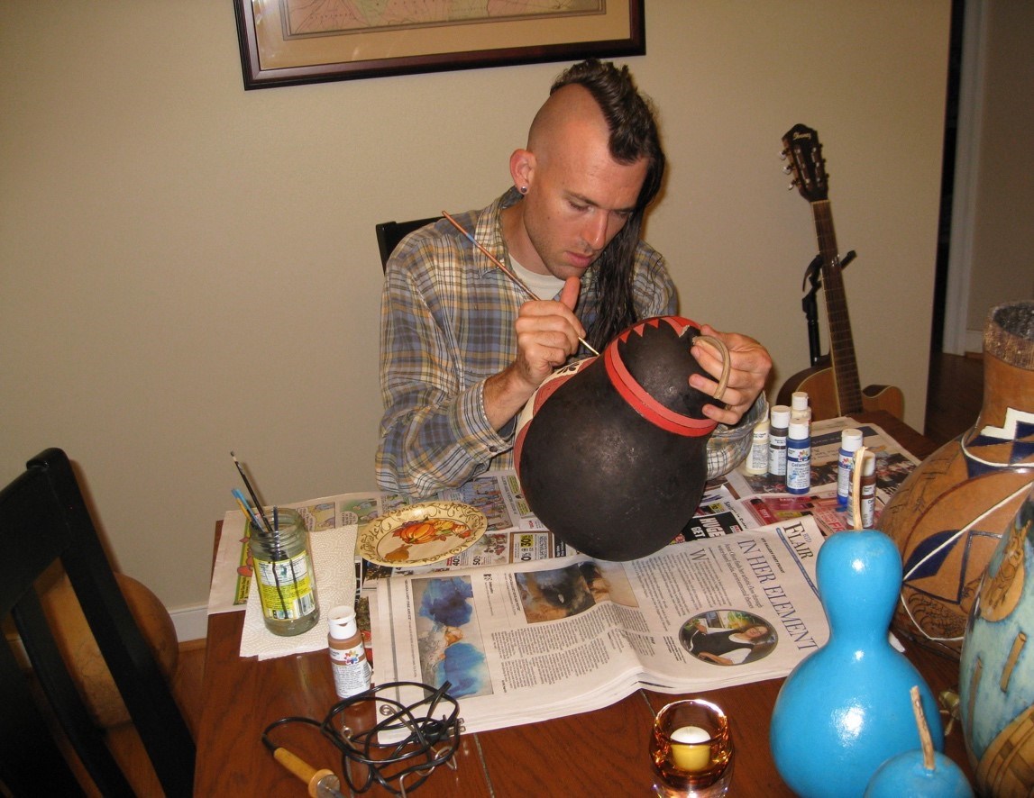 Artist Ethan Brown works on a gourd painting.