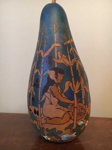 Ethan Brown Three Sisters Gourd A gourd painted to show a woman kneeling in a field of corn.