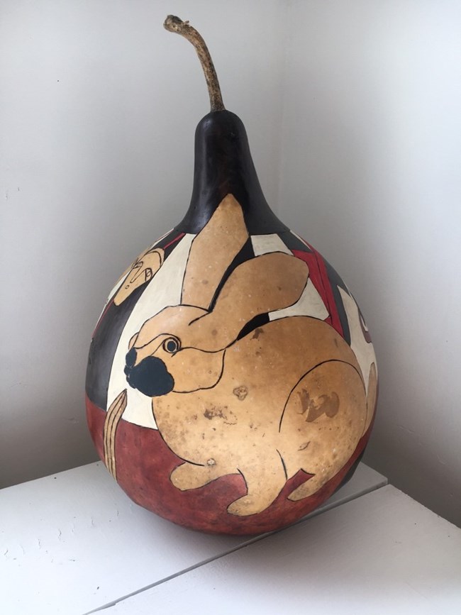 A gourd painted to show a rabbit and other figures.